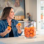 A Smiling Woman Holding Two Tangerines Copy